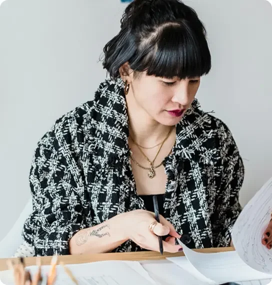 Woman with black hair reading papers at her desk