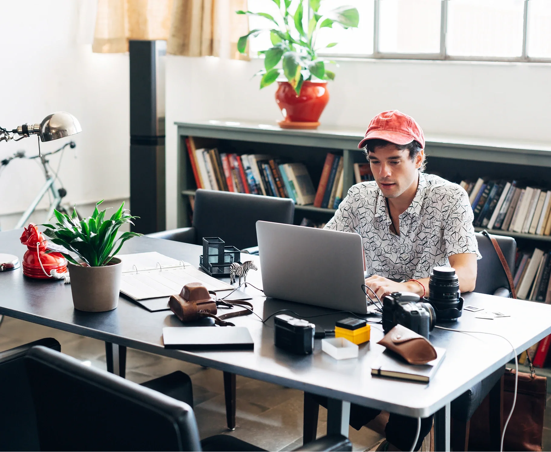 A man in a red baseball cap in front of the laptop