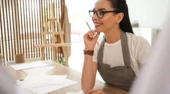 Smiling woman in apron with pencil in hand