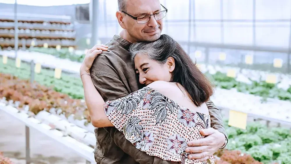A middle-aged man and woman embrace in a plant nursery. If you want to ensure that your estate goes to specific people, creating a last will and testament is the best way to fulfill those wishes.