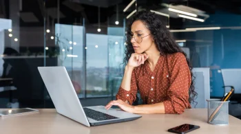 Woman in glasses working on a laptop in an office