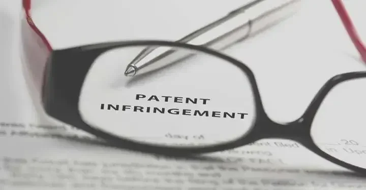  A pair of reading glasses rests on top of a document titled "patent infringement."