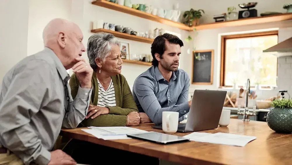 An image of a family with elderly parents in a living room looking at their living will together.