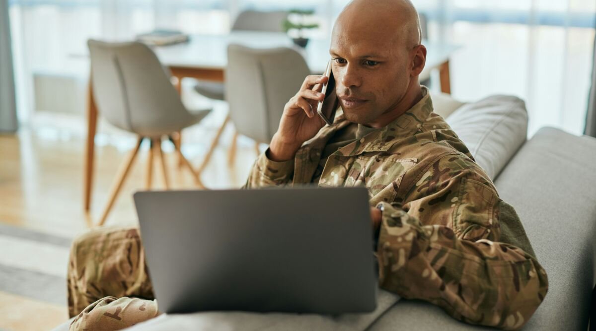 A United States Army soldier reviews a contract on his laptop while discussing it with his contract attorney.