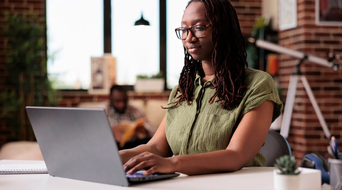 Woman in green shirt working on a laptop indoors