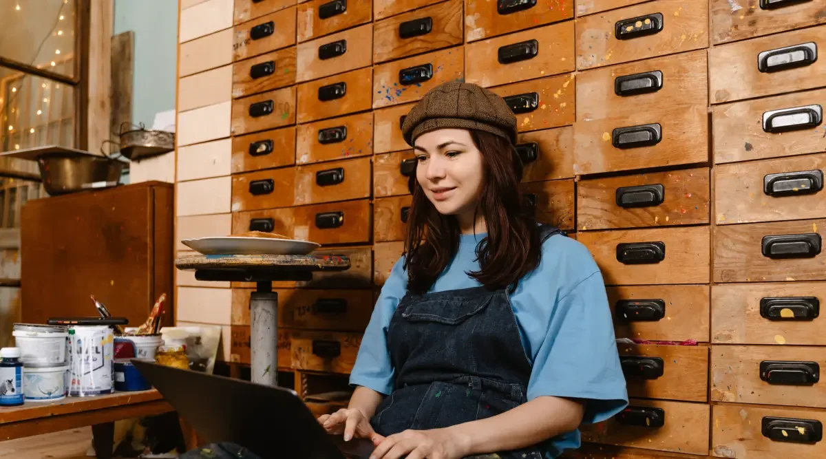 An artist sits in her studio and reads about patent applications online.