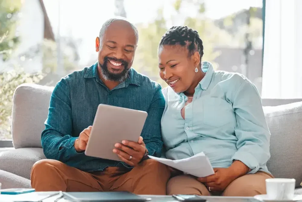 A couple is checking on a tablet about what to include in their last will and how to create a power of attorney to handle their assets.