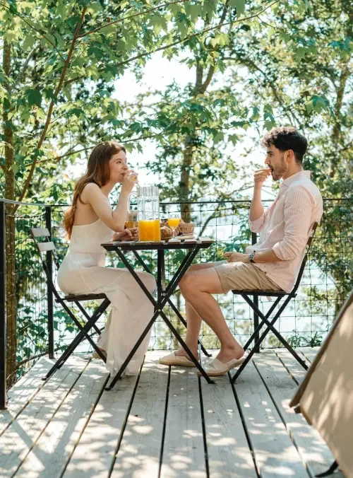 A married couple eating at a dining table outside while discussing what should be included in their postnuptial agreement