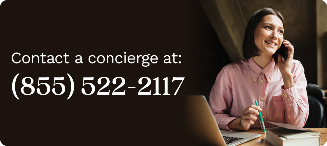 Woman in a pink blouse sitting at her desk, talking on the phone