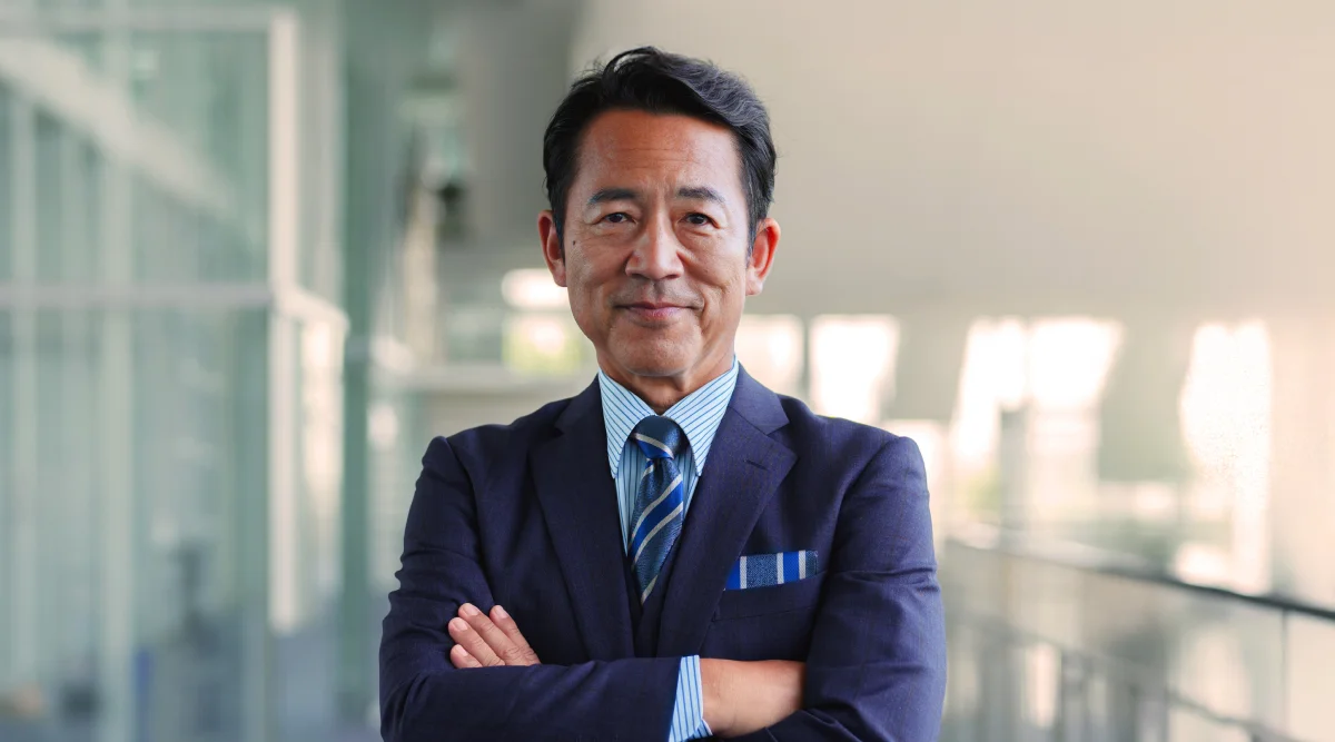 A trademark attorney stands with his arms crossed confidently. He's wearing a suit and has a light, reassuring smile on his face.