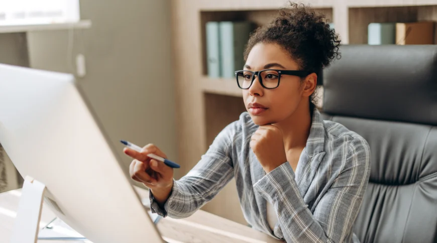 Woman typing on laptop in bright room, exploring the difference between EIN vs. TIN tax numbers