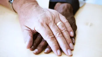 Two hands hold each other clearly displaying a wedding band