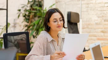 Woman reading document, seated at desk