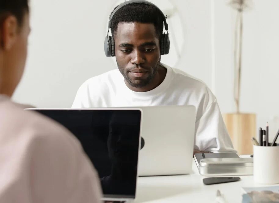 A man wearing headphones typing on a laptop in a quiet coworking space