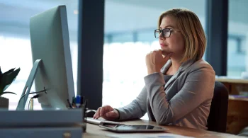 Woman thoughtfully working on a desktop computer