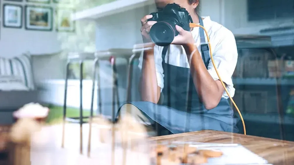 Woman takes a photo of an item on a table.