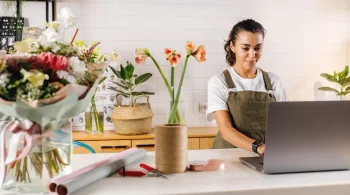 Florist using a laptop surrounded by flowers