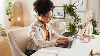 A woman typing on her laptop at a desk.