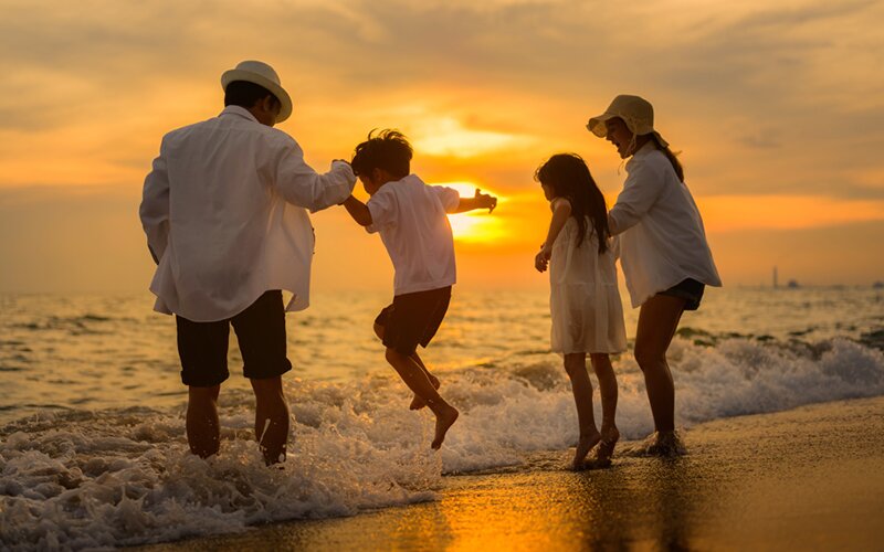 An image of a family of 4 playing on the beach and enjoying their vacation.