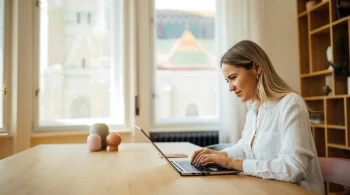 Woman typing on laptop in bright room