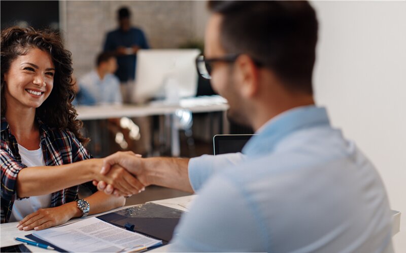 An image of a female job applicant and a male employee shaking hands.