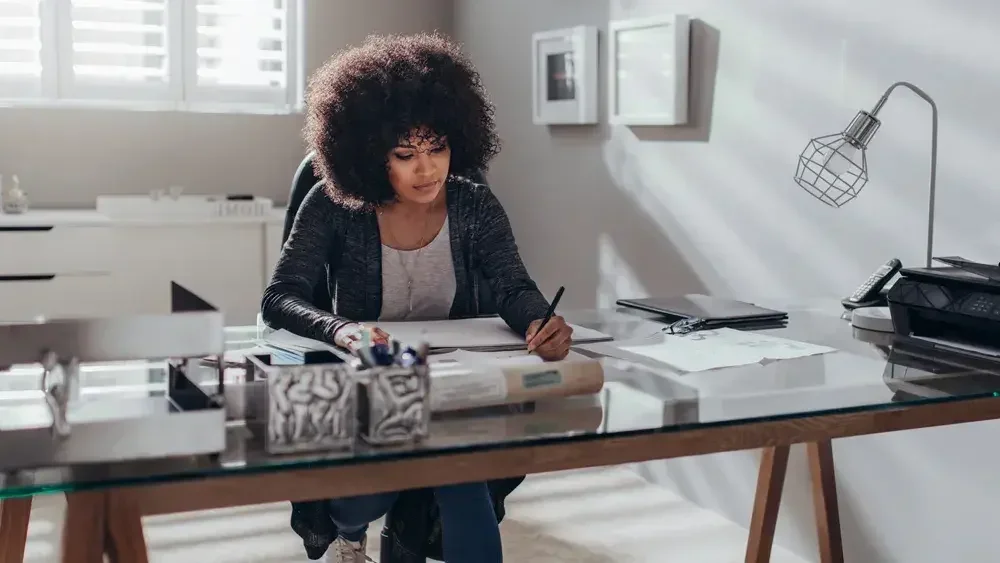A woman at a desk writing with a pen