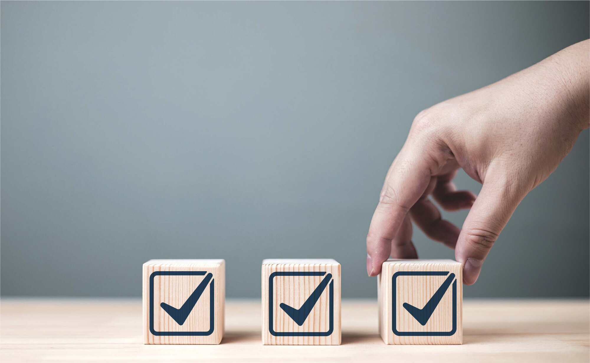 An image of a person placing three wooden cubes with a checkmark.