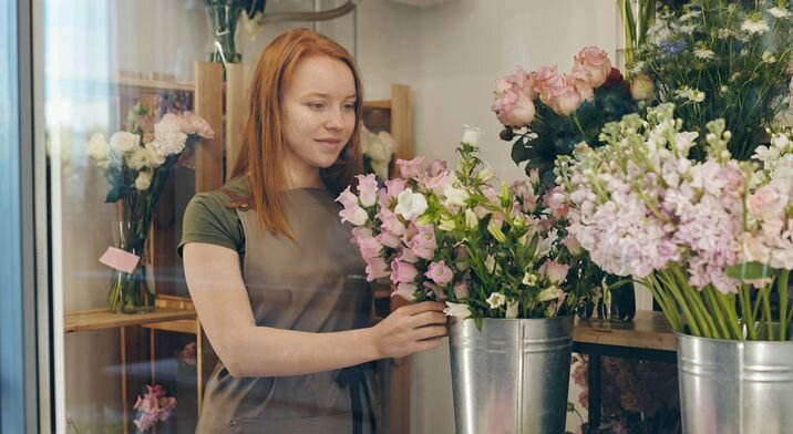 A florist makes an arrangement in her shop