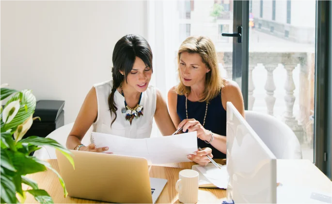 Two women discuss a project in a modern office