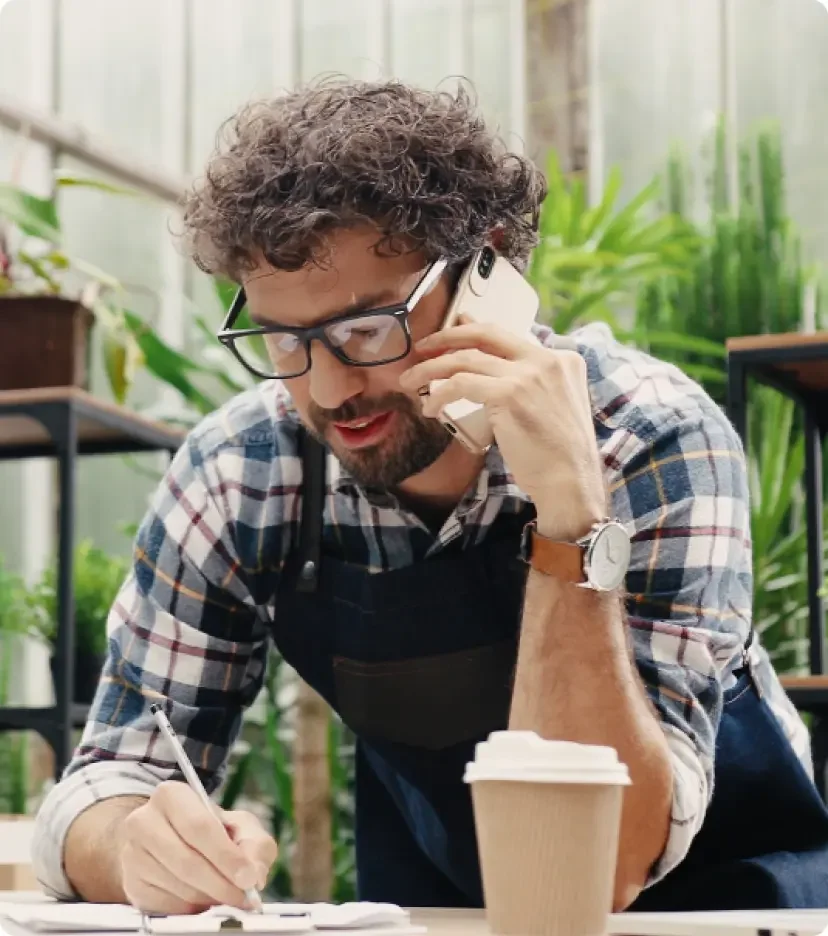 Man with brown hair surrounded by plants works on legal documents 