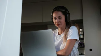 Woman with headphones, engaged with laptop