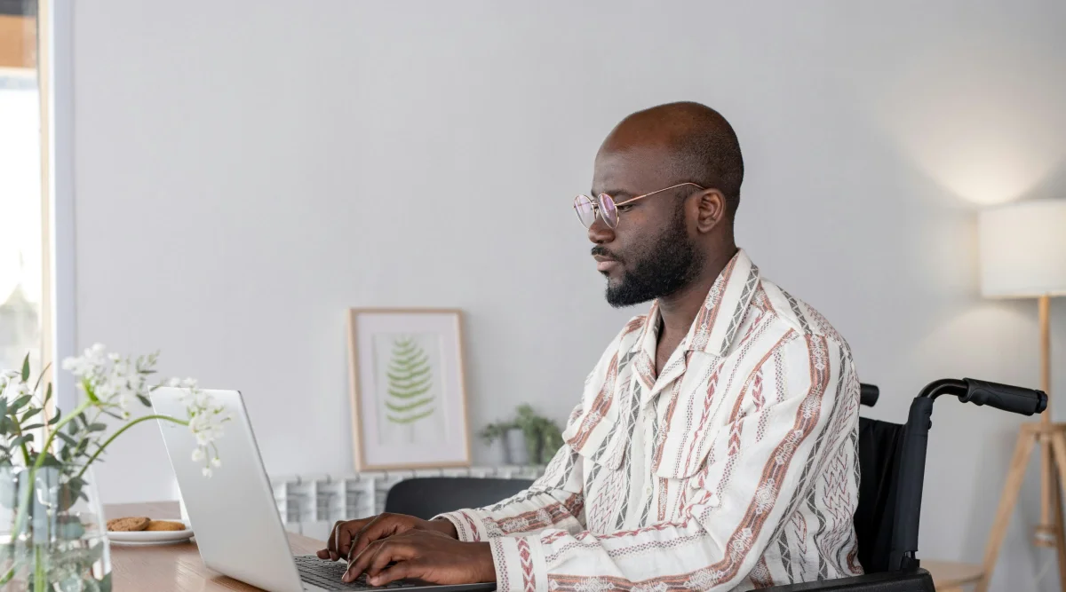 Man in wheelchair working on a laptop in a stylish room