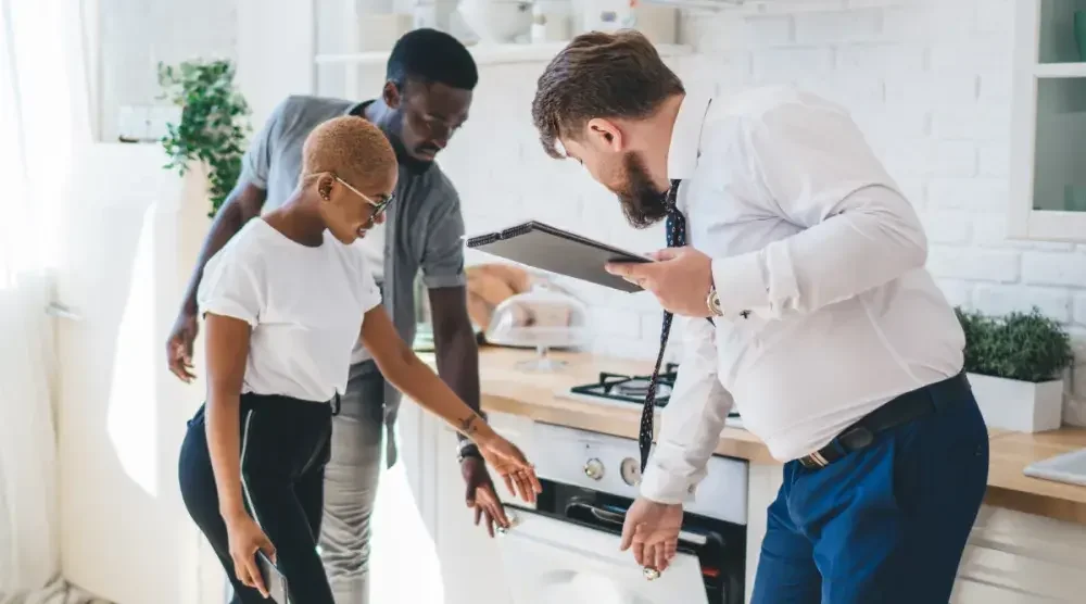 A couple walks around a kitchen with their real estate agent.