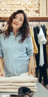 A woman folding a shirt in a clothing retail shop who was hired as an independent contractor