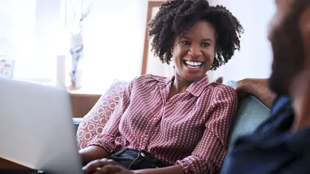 A woman sits on a couch with an open laptop after creating her Florida last will and testament. In Florida, individuals must be at least 18 years old or an emancipated minor to create a will. 