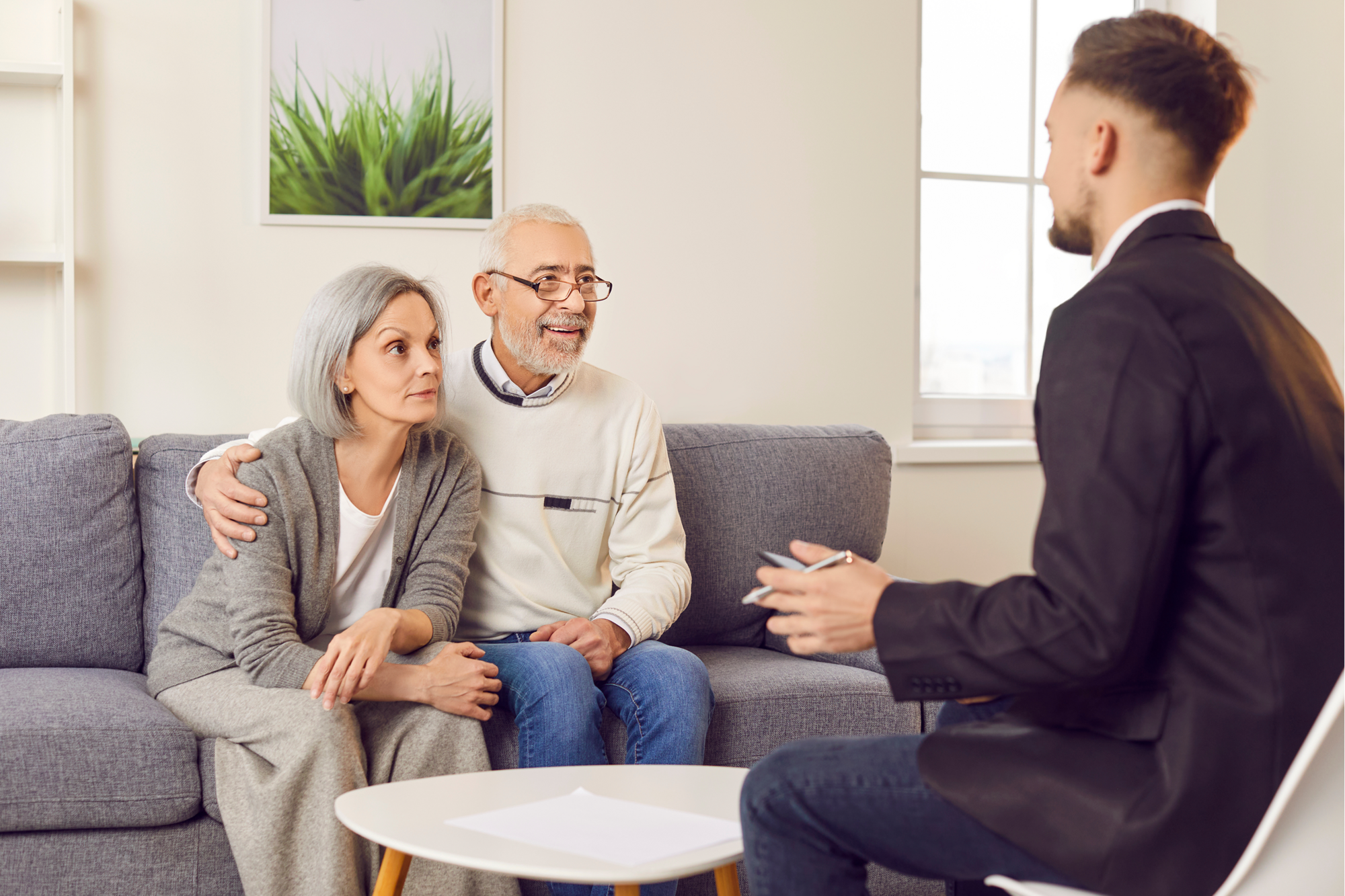 An older couple is sitting on a sofa and talking to an attorney about the importance of selecting the right trustee.