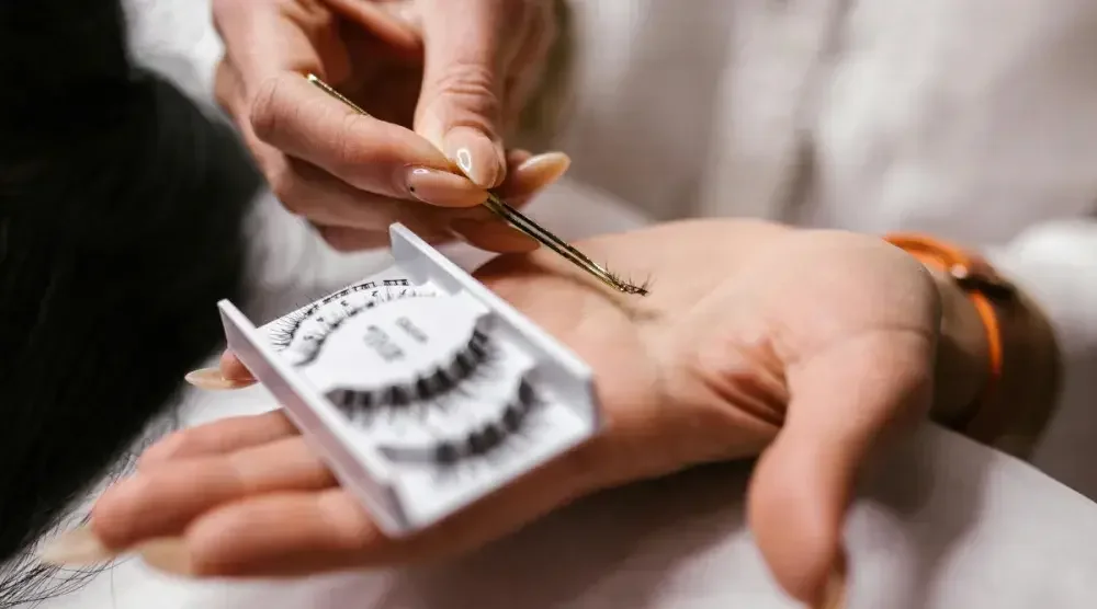 Close up of hands holding a tray of lashes and applicator.