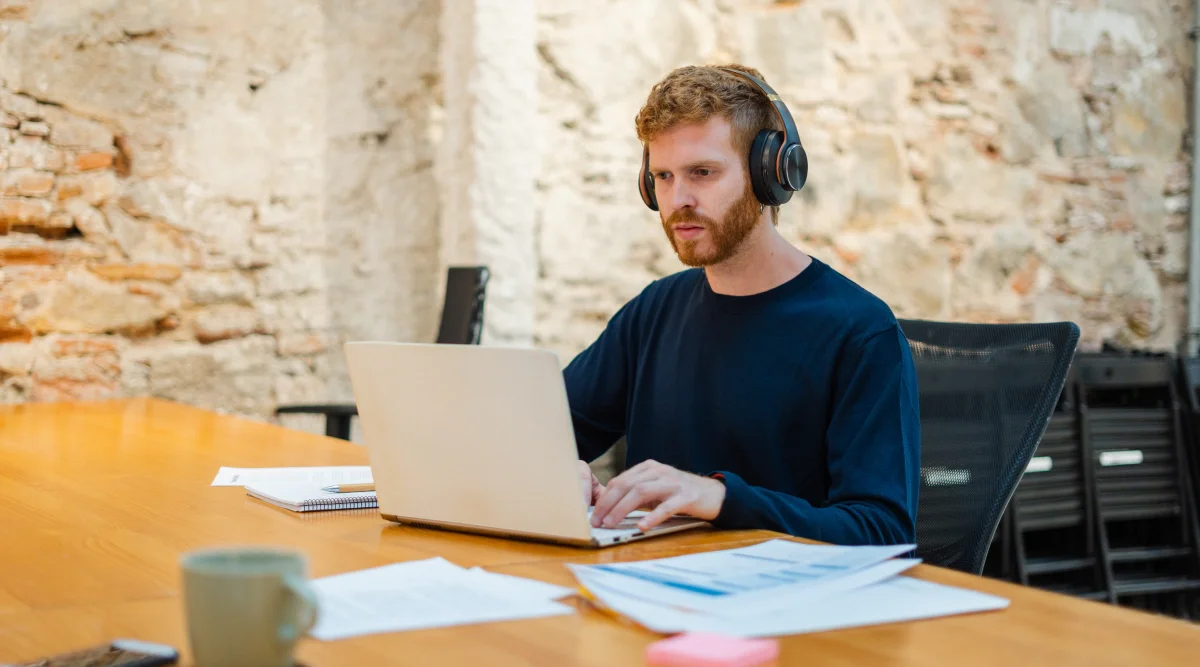 Man with headphones working on a laptop in a rustic office