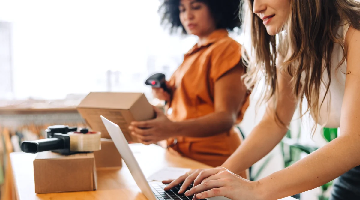 Two women packing and scanning boxes in a store