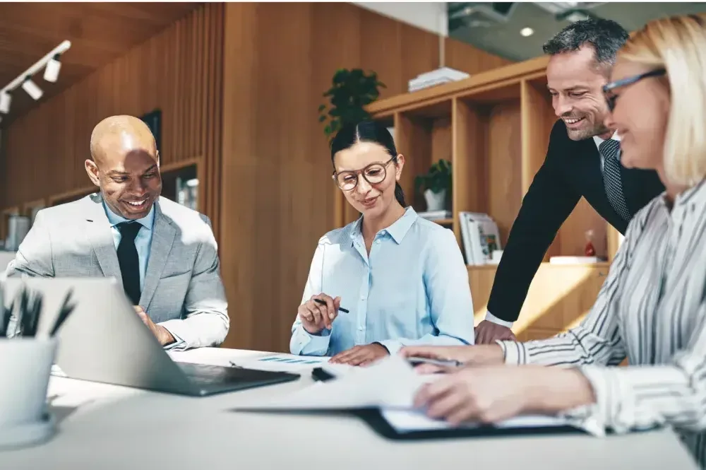 Four people seated around a conference table smile while deciding to become a single member or multi member LLC. The &quot;member&quot; LLC rules can be tricky. Read this article to learn what might work for you.