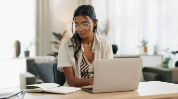 Woman with glasses working on a laptop at home