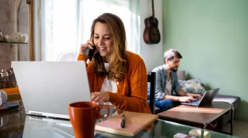 Woman on phone with laptop, man in background