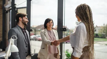 Three people shaking hands in a bright office