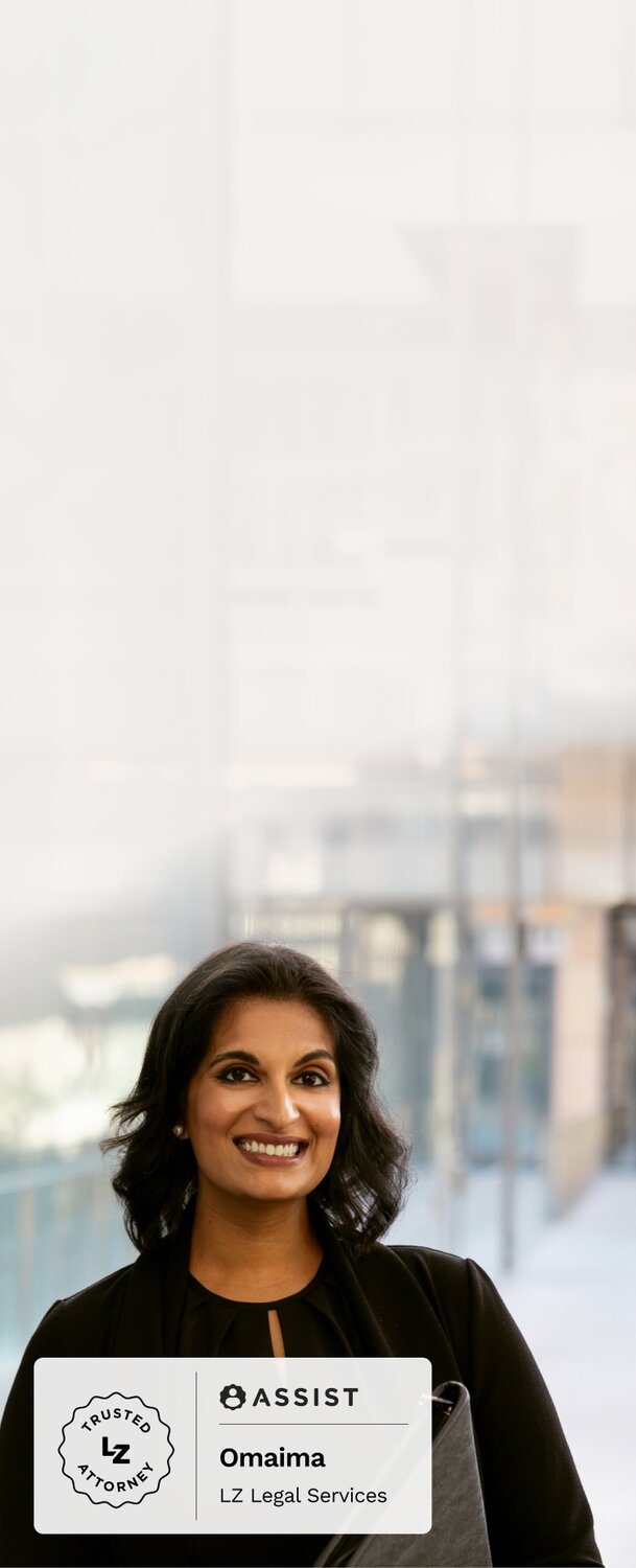 Woman wearing a black business suit smiles while holding her laptop