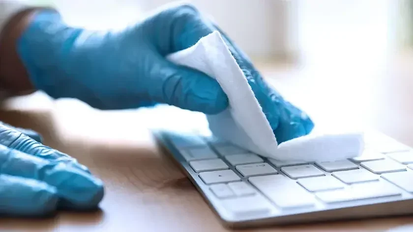 A person wearing blue latex gloves sanitizes a keyboard with an antibacterial wipe. Before you launch your house-cleaning business, learn what's required.