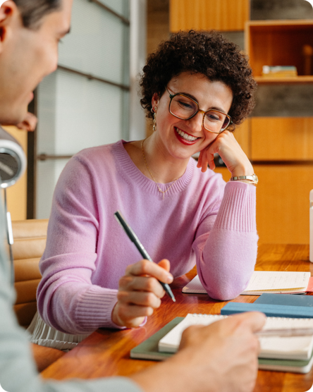 Woman with curly hair and pink shirt takes notes on how to improve their business 