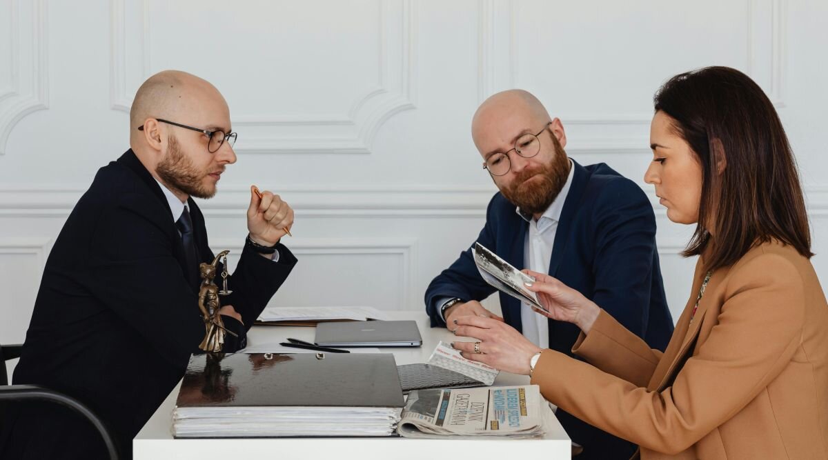A young couple reviewing documents with an attorney in his office.