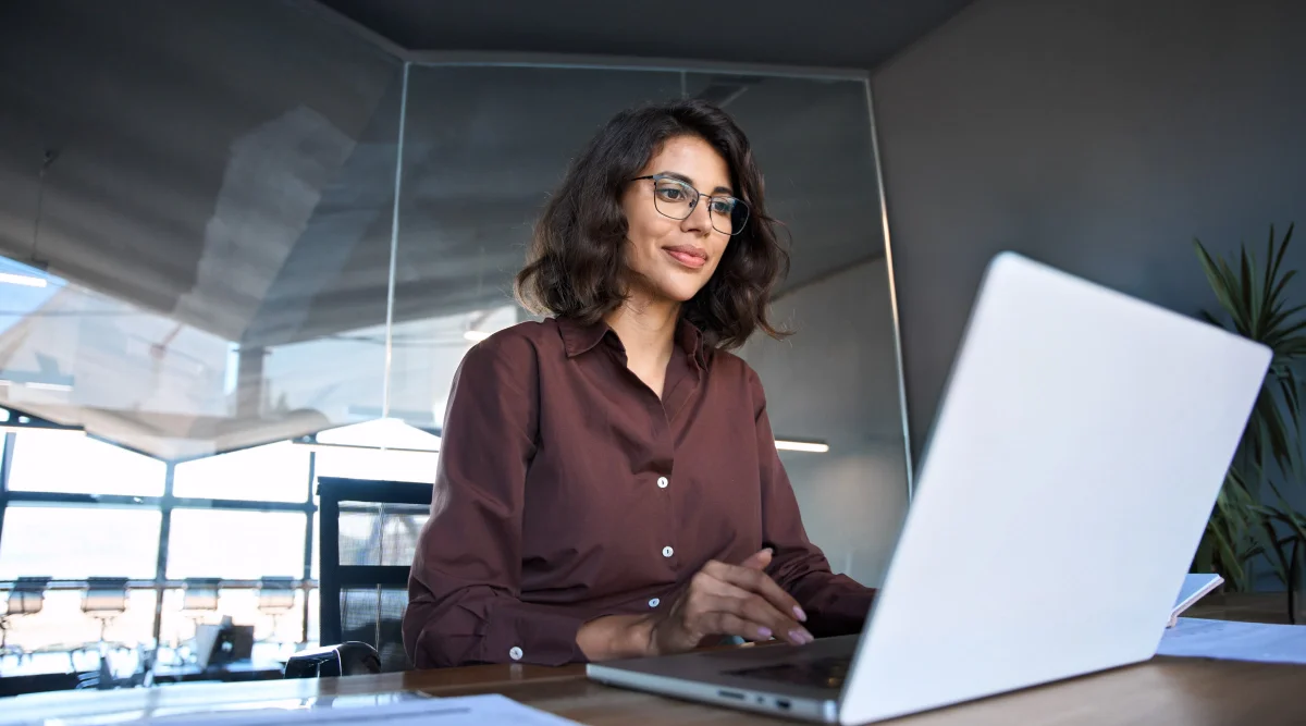 Woman working on a laptop in a glass-walled office