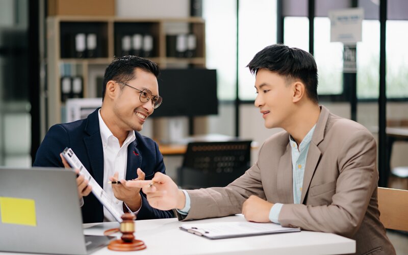 An image of 2 people discussing the terms of a personal management agreement in an office.