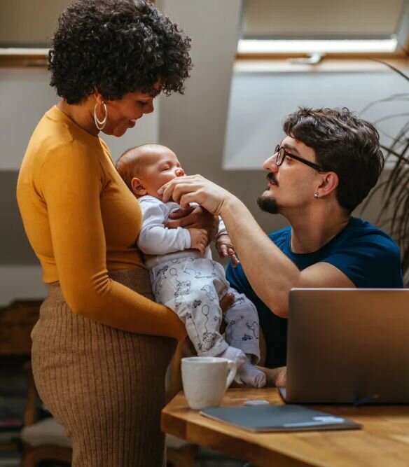 A couple standing with a baby in a warm home office